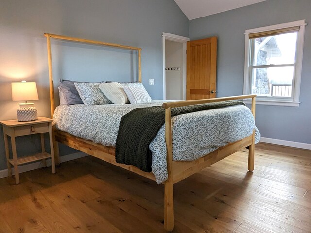 bedroom with hardwood / wood-style flooring and lofted ceiling