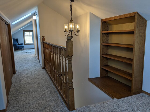 hallway with carpet, a chandelier, and vaulted ceiling