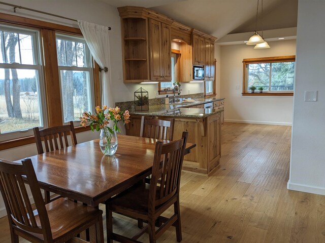 dining space featuring sink, plenty of natural light, lofted ceiling, and light hardwood / wood-style flooring