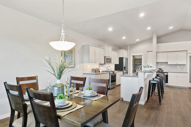 dining area featuring dark hardwood / wood-style flooring, vaulted ceiling, beverage cooler, and sink