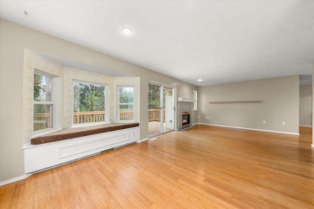 unfurnished living room with light wood-type flooring and a textured ceiling