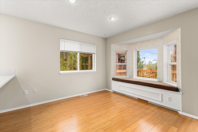 empty room with light hardwood / wood-style floors and a textured ceiling