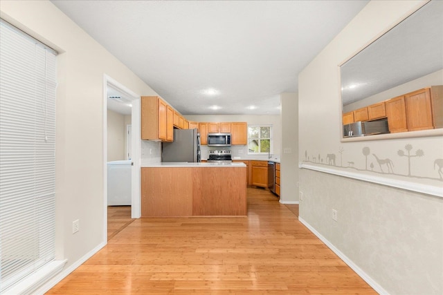 kitchen featuring kitchen peninsula, light brown cabinets, light wood-type flooring, and stainless steel appliances