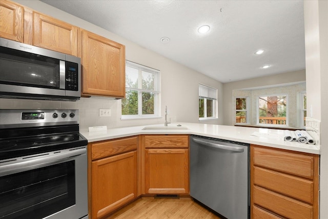 kitchen with a healthy amount of sunlight, light hardwood / wood-style floors, sink, and appliances with stainless steel finishes