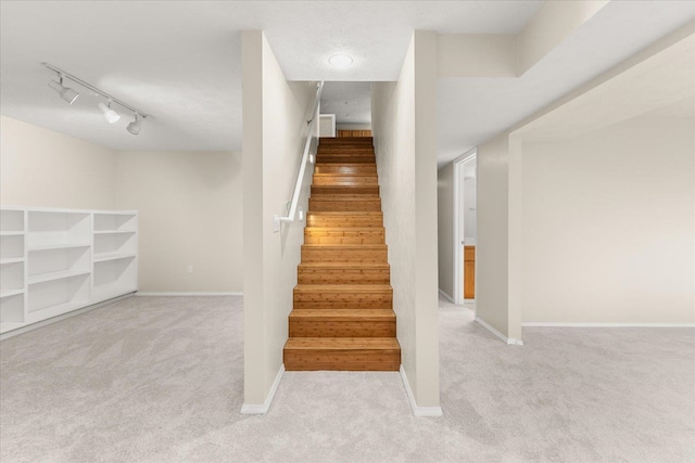 stairs featuring carpet flooring, a textured ceiling, and track lighting