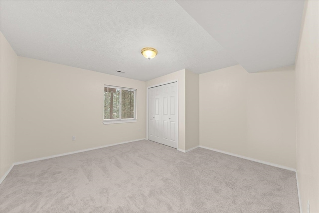 empty room featuring light carpet and a textured ceiling