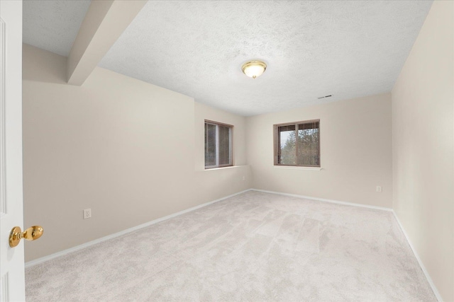 carpeted empty room featuring beam ceiling and a textured ceiling