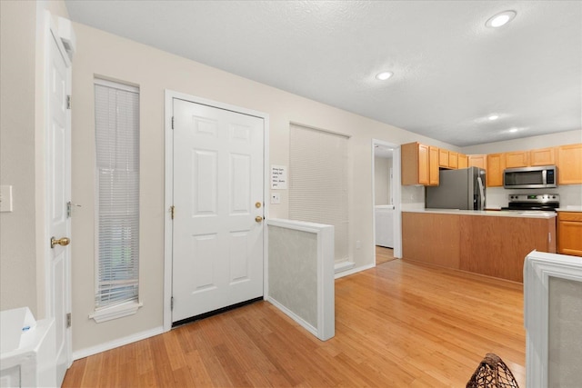 kitchen with light brown cabinetry, stainless steel appliances, and light wood-type flooring