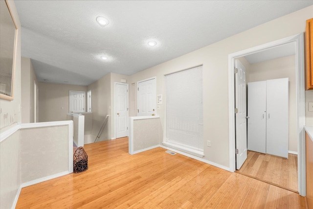 interior space with a textured ceiling and light hardwood / wood-style flooring