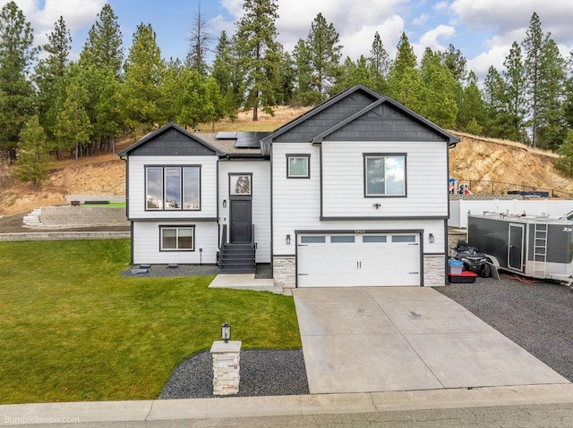 bi-level home featuring a front yard, solar panels, and a garage