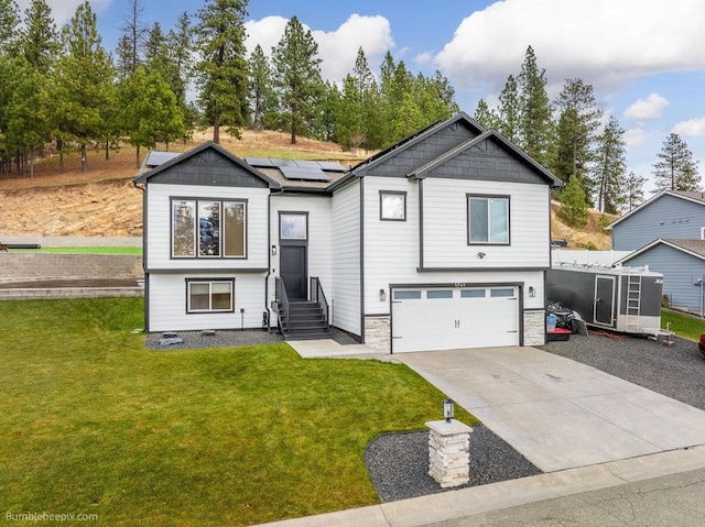 split foyer home with solar panels, a garage, and a front lawn