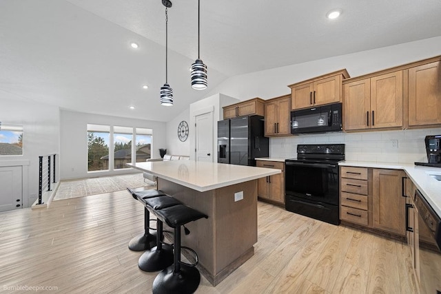 kitchen featuring light hardwood / wood-style flooring, decorative light fixtures, lofted ceiling, decorative backsplash, and black appliances