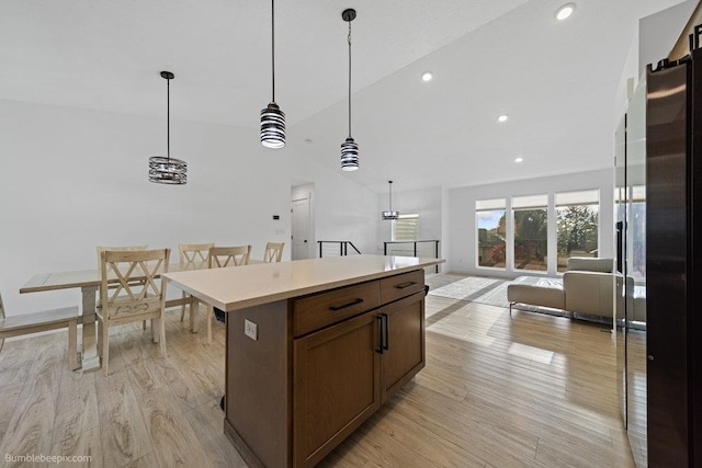 kitchen featuring pendant lighting, a center island, light wood-type flooring, and vaulted ceiling