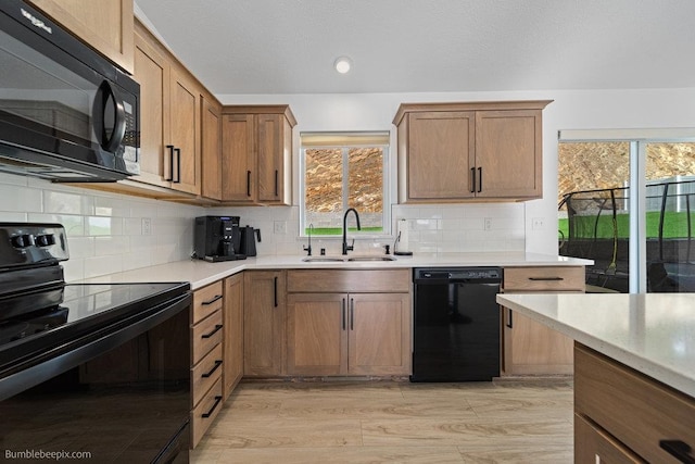 kitchen featuring light wood-type flooring, decorative backsplash, sink, and black appliances