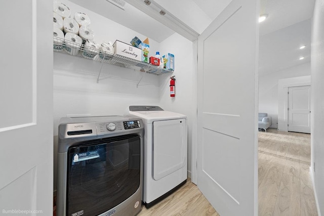 laundry area featuring washer and clothes dryer and light hardwood / wood-style flooring