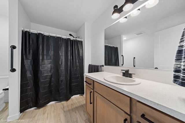 bathroom with hardwood / wood-style flooring, vanity, toilet, and tasteful backsplash