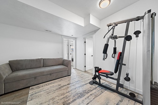 exercise room with vaulted ceiling, hardwood / wood-style floors, and a textured ceiling