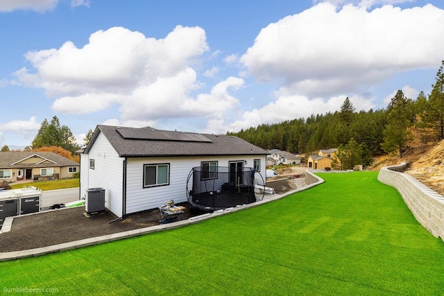 rear view of house with solar panels, a yard, and central AC