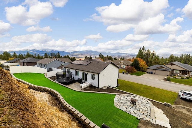 exterior space featuring a lawn, a mountain view, a fire pit, and solar panels