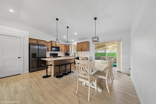 dining room with sink, light hardwood / wood-style floors, and lofted ceiling