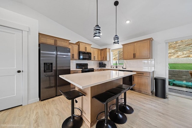 kitchen with backsplash, pendant lighting, lofted ceiling, black appliances, and light wood-type flooring