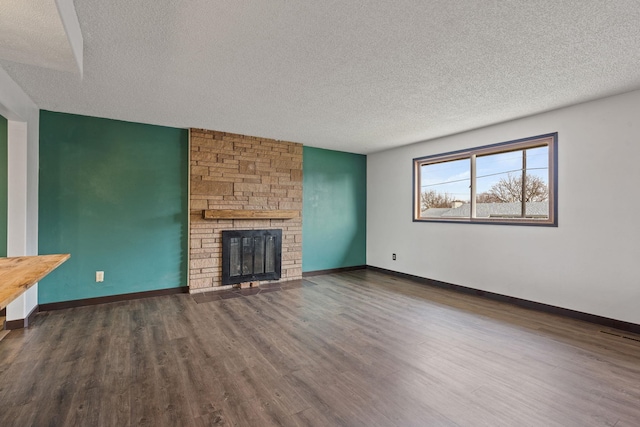 unfurnished living room with dark hardwood / wood-style floors, a stone fireplace, and a textured ceiling