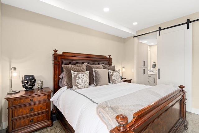 bedroom with a barn door and connected bathroom