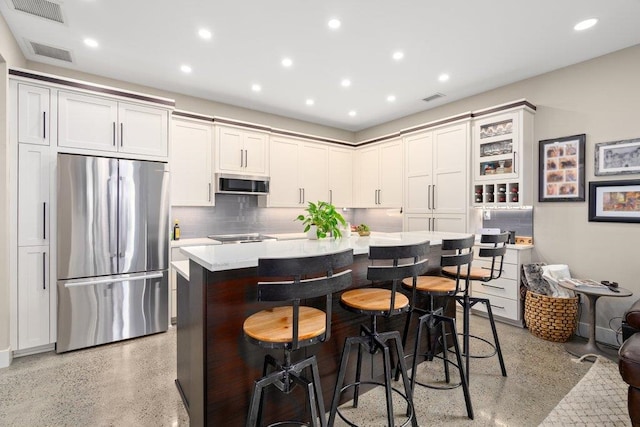 kitchen with a breakfast bar, a center island, stainless steel appliances, and white cabinets