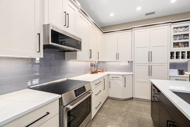 kitchen with white cabinets, light stone countertops, appliances with stainless steel finishes, and tasteful backsplash