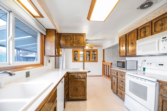 kitchen with kitchen peninsula, backsplash, white appliances, ceiling fan, and sink