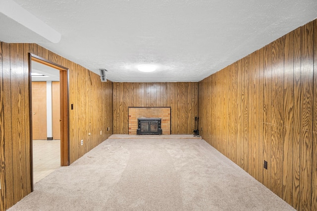 unfurnished living room with carpet, a textured ceiling, and a brick fireplace