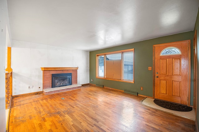 entrance foyer featuring wood-type flooring, a brick fireplace, and baseboard heating