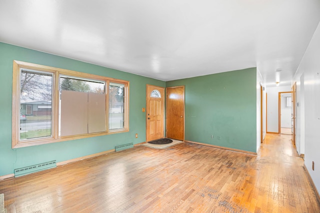 unfurnished living room with baseboard heating and light hardwood / wood-style flooring