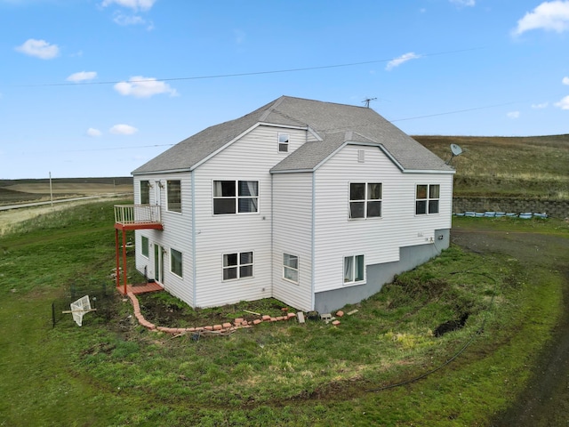 rear view of house with a balcony and a lawn