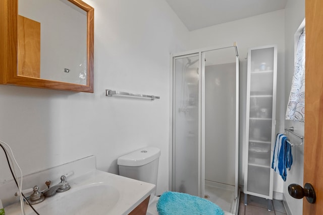 bathroom featuring tile patterned flooring, vanity, toilet, and a shower with door