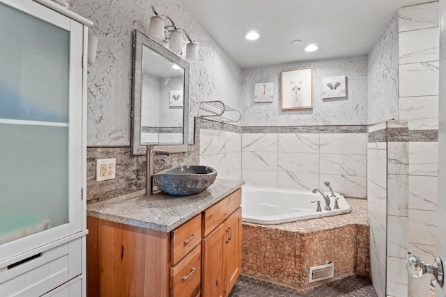 bathroom featuring vanity, tile walls, and tiled bath