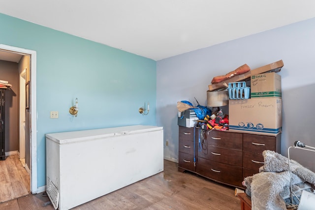 bedroom with hardwood / wood-style flooring and refrigerator