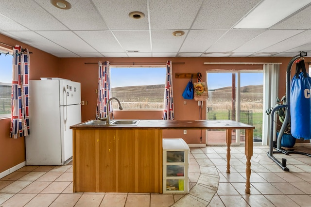 kitchen featuring a drop ceiling, sink, light tile patterned floors, white refrigerator, and a mountain view