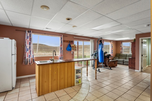 kitchen featuring a drop ceiling, sink, light tile patterned floors, white refrigerator, and a mountain view