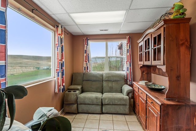 living room featuring a drop ceiling and light tile patterned floors