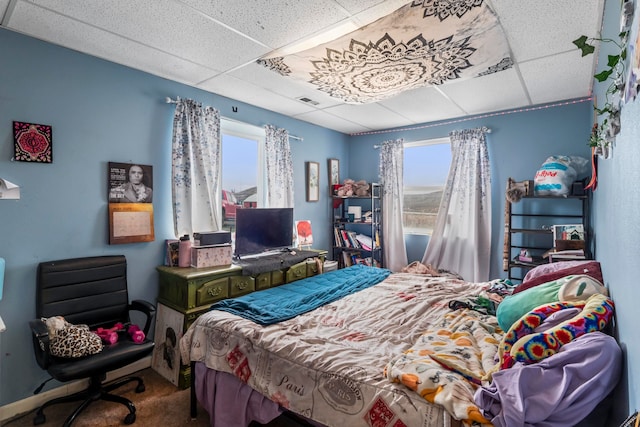 carpeted bedroom featuring a paneled ceiling and multiple windows