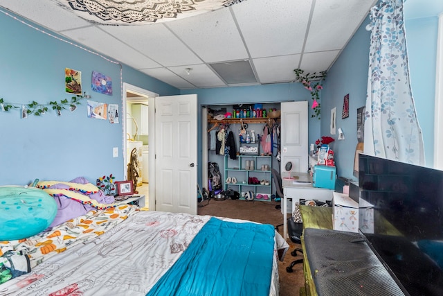 carpeted bedroom with a paneled ceiling, a closet, and washer / dryer