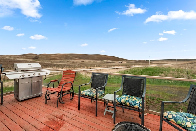 wooden deck with a mountain view, a rural view, and a grill