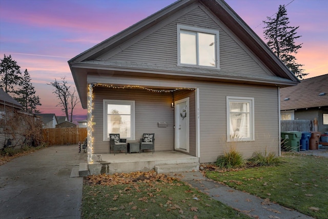 back house at dusk featuring covered porch