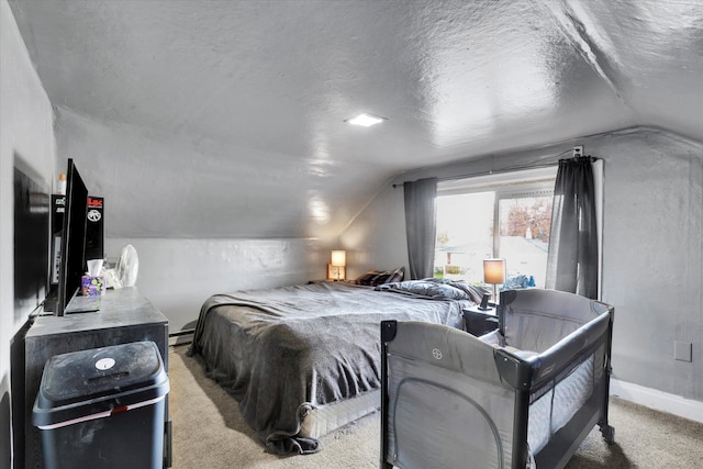 bedroom featuring a textured ceiling, light carpet, and lofted ceiling