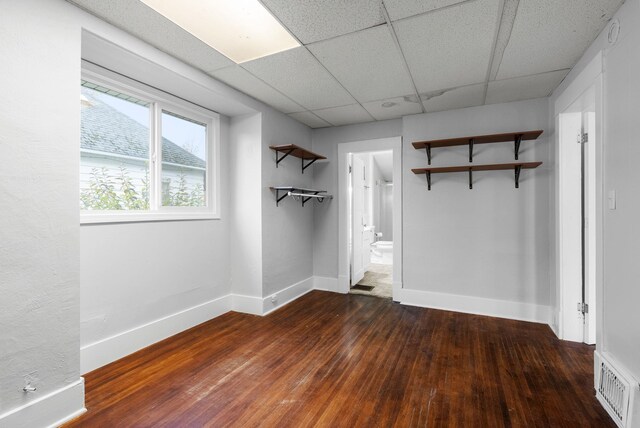 empty room with a paneled ceiling and dark hardwood / wood-style floors