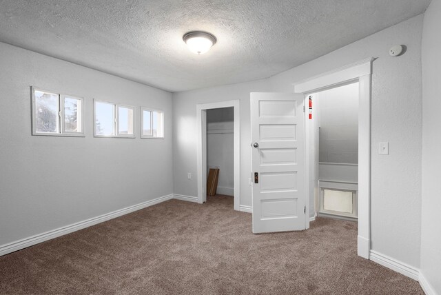 unfurnished bedroom with heating unit, electric panel, carpet floors, and a textured ceiling