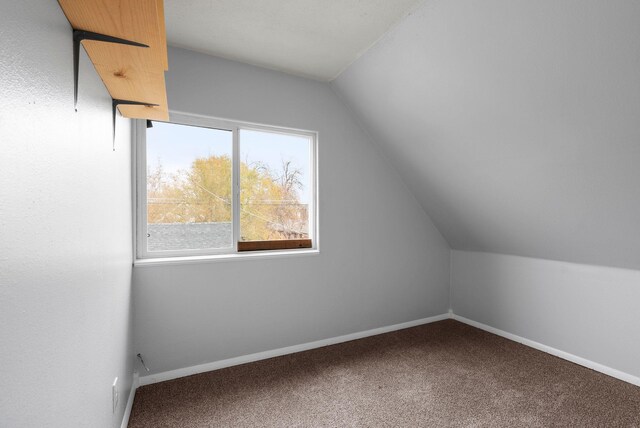 unfurnished bedroom with a walk in closet, a textured ceiling, carpet floors, a closet, and lofted ceiling