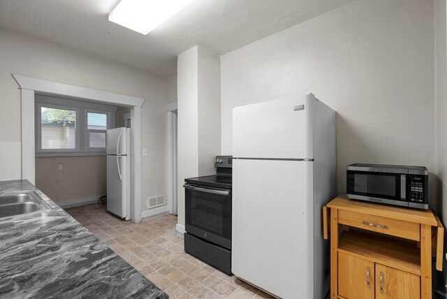 kitchen with white cabinetry, sink, white dishwasher, and dark stone counters