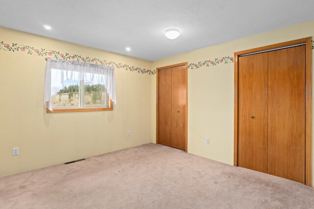 unfurnished bedroom with multiple closets and carpet floors